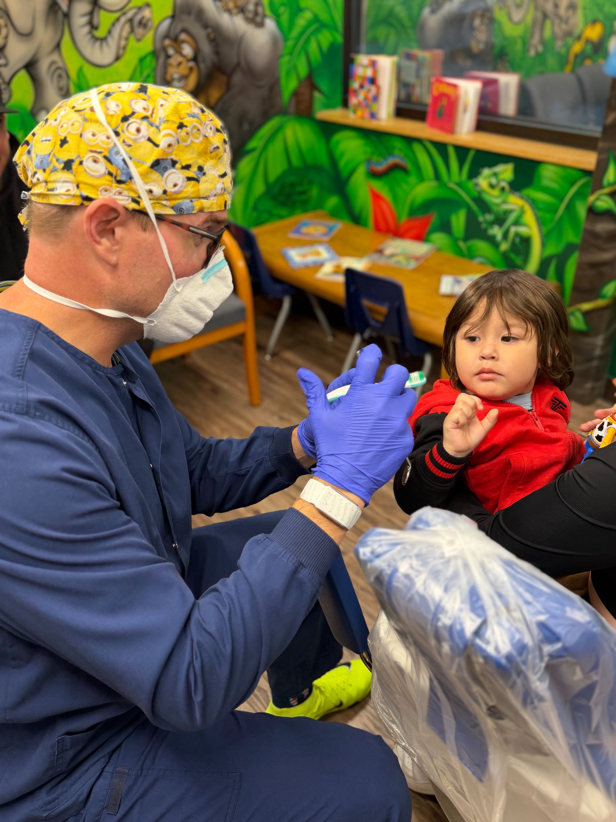 Dr. Bumann handing a toothbrush to a young patient